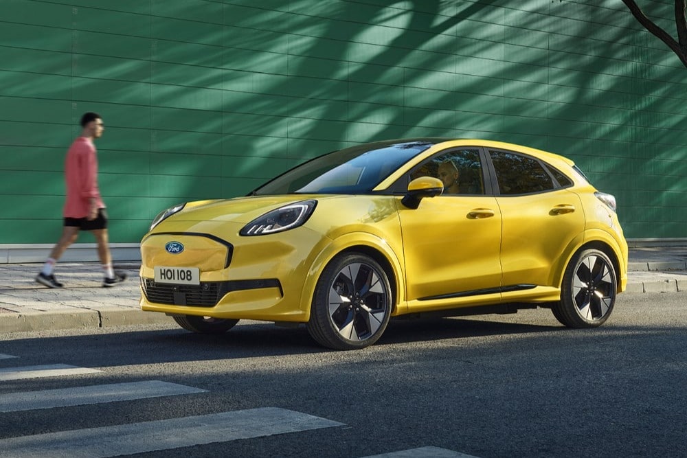 A yellow Ford Puma Gen-E parked by the side of the road.