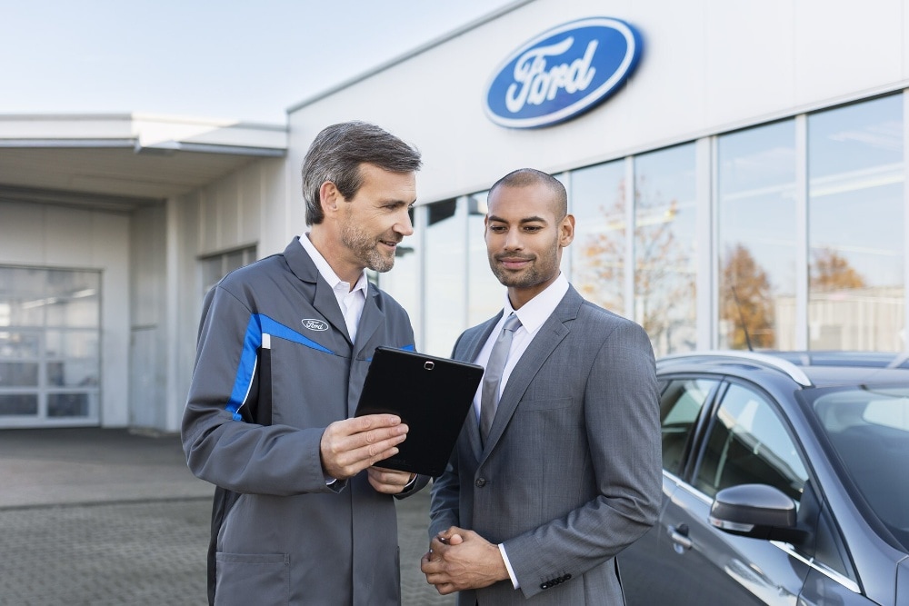 Two men in front of Ford dealership