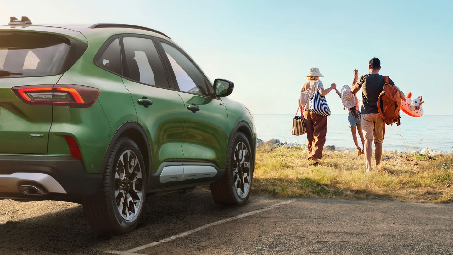 a green Ford Kuga parked whilst a family walks away towards the beach