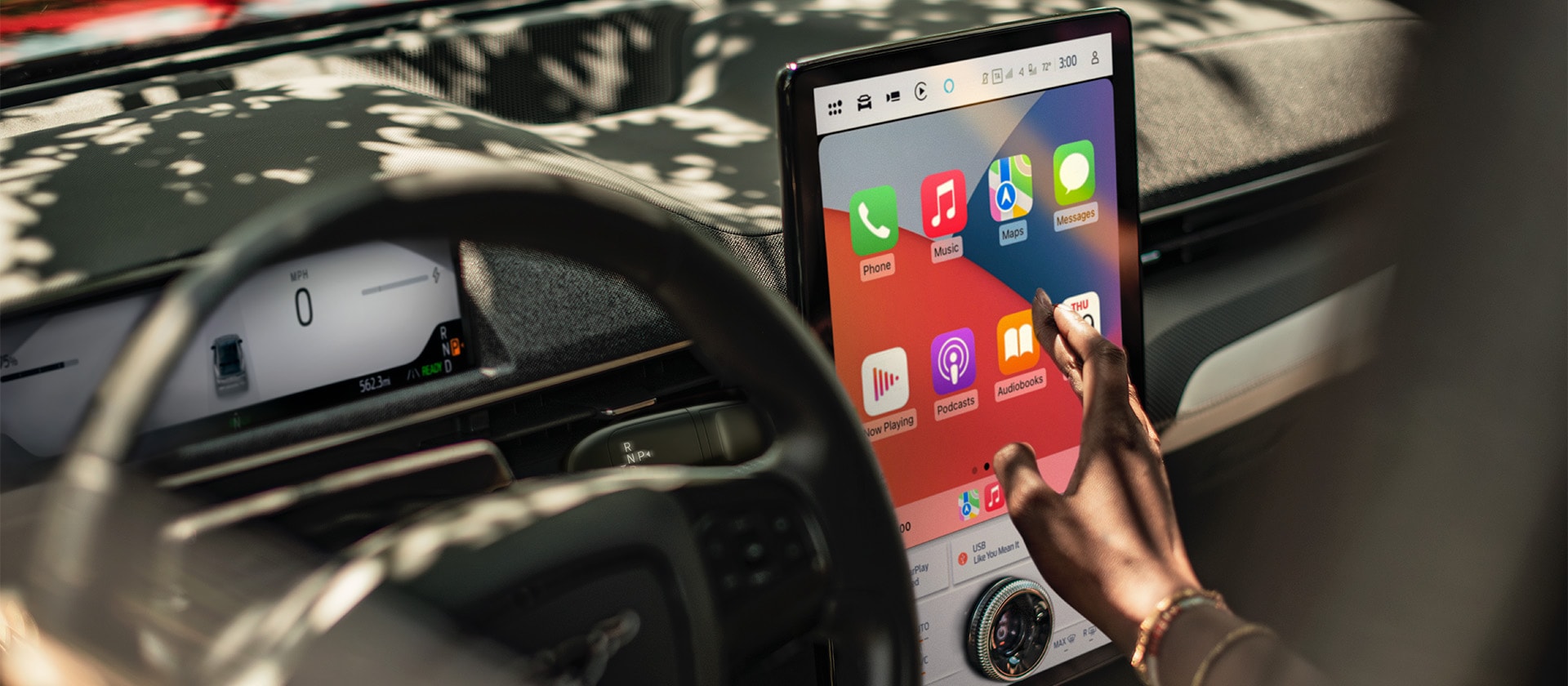 A close up on the driver of a Ford Mustang Mach-E interacting with the large 15.5" SYNC 4 touchscreen showing Apple CarPlay. 