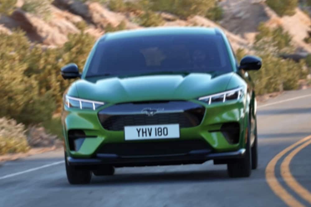 Front view of green Ford Mustang Mach-E driving on mountain road.