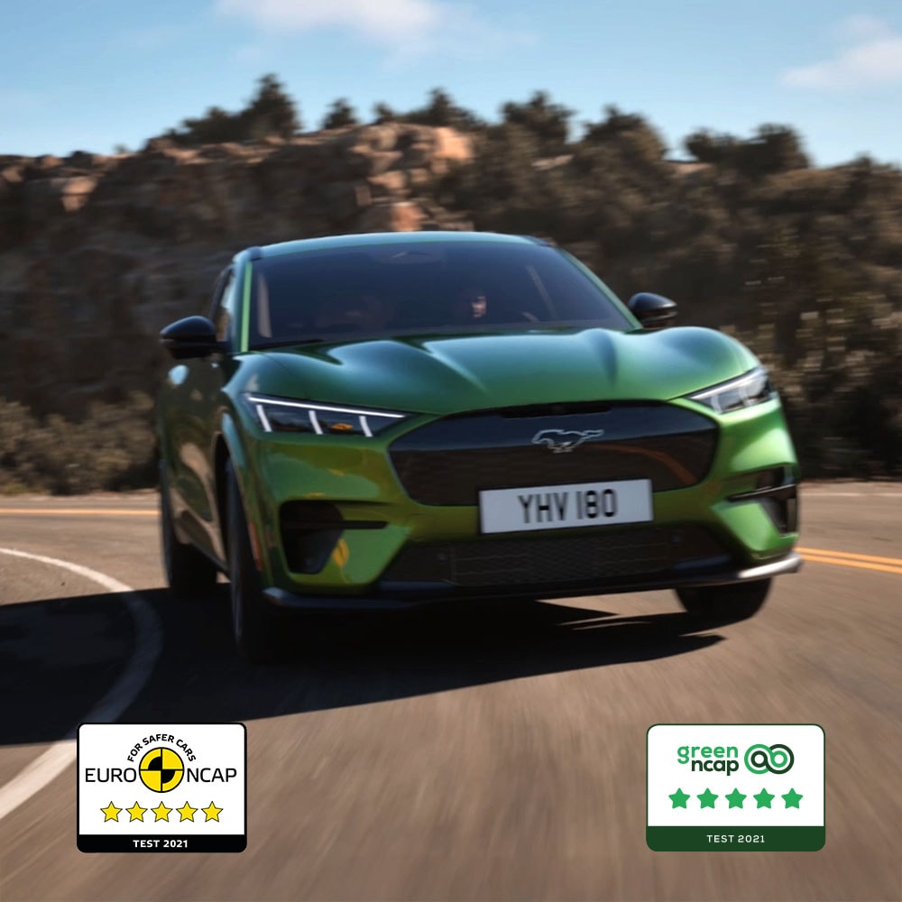 A Ford Mustang Mach-E GT in Eruption Green driving on a mountain road.