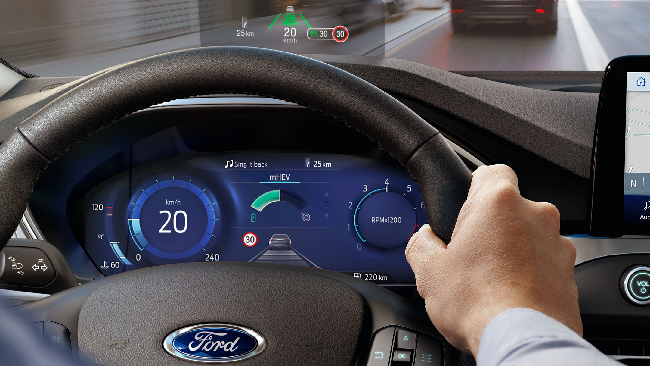 Hand holding a steering wheel with a small monitor above the dashboard