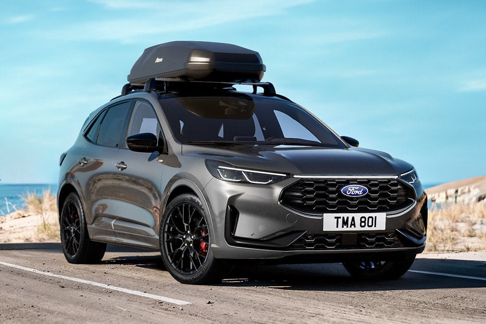 A grey Ford Kuga Black Package vehicle, with a close-up of 20" black alloy wheels and black exterior details with a roofbox.