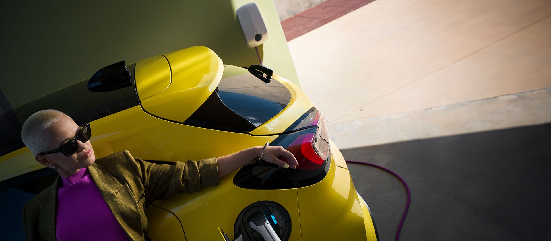 A close up on the rear of a yellow electric Ford Puma Gen-E®, plugged in to a home wallbox.