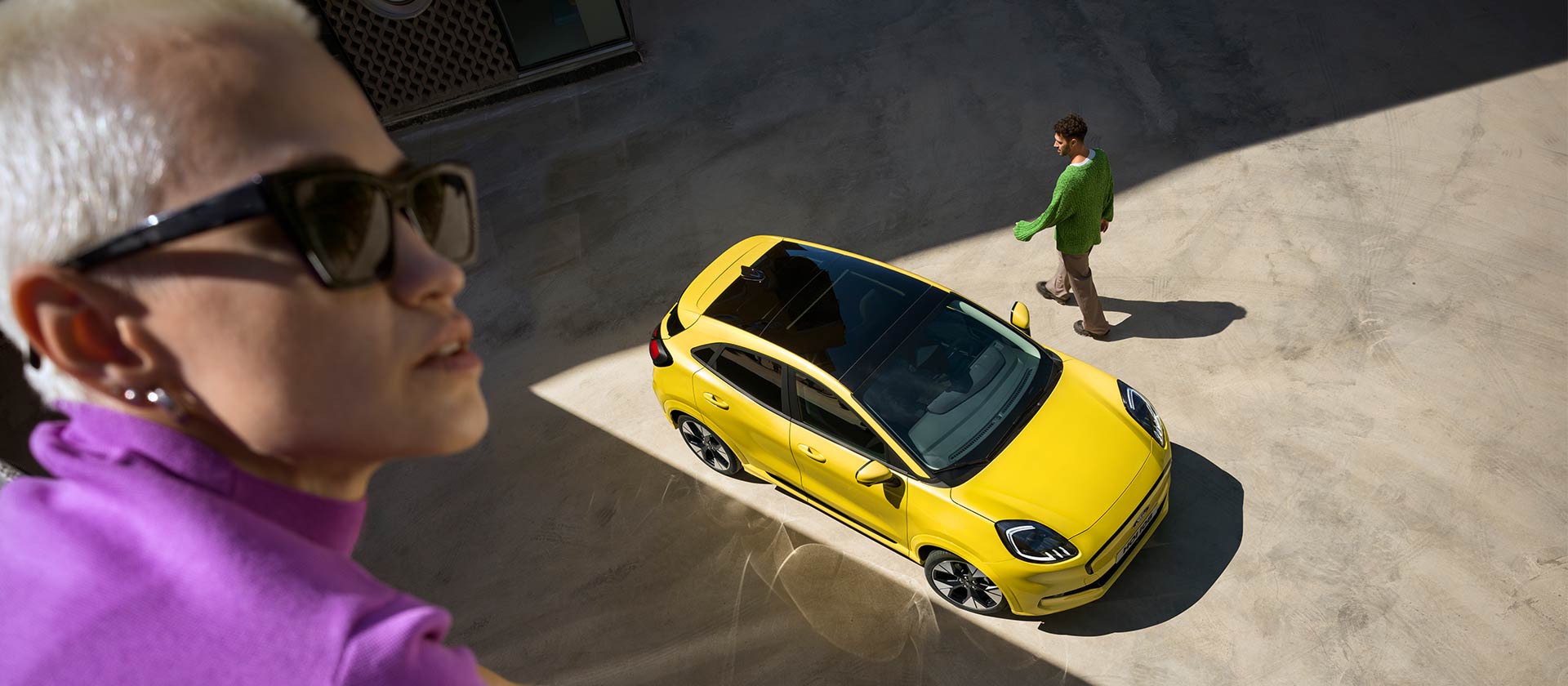 Birds eye view of a yellow electric Ford Puma Gen-E®. Person in purple in the foreground.