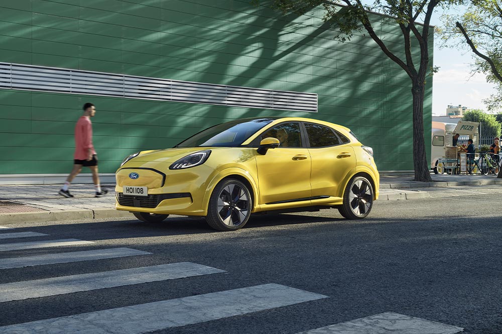 Image of a yellow Ford Puma Gen-E driving on a main road.