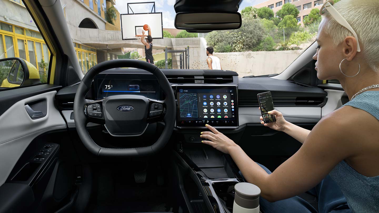 The interior of the electric Ford Puma Gen-E®, with a person wirelessly syncing their mobile phone to the large touchscreen.