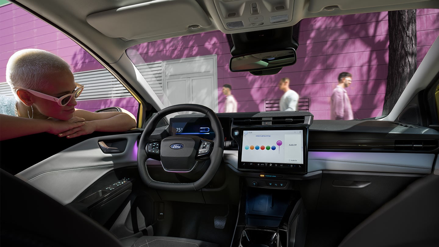 Person looking at the interior of the new Ford Puma Gen-E®, showing the large touchscreen and ambient lighting.