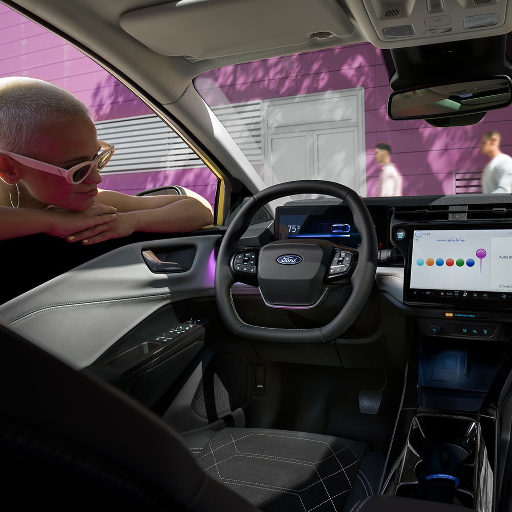 The interior of the electric Ford Puma Gen-E®, with a person looking at the large infotainment screen through the window.