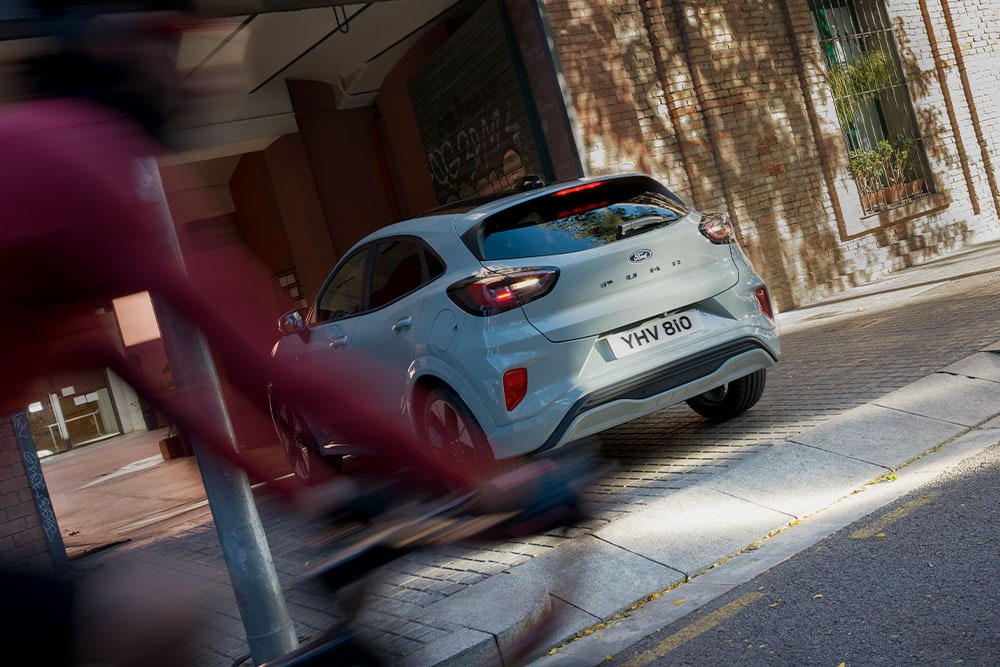 Rear view of a grey Ford Puma parked in a leafy city street.