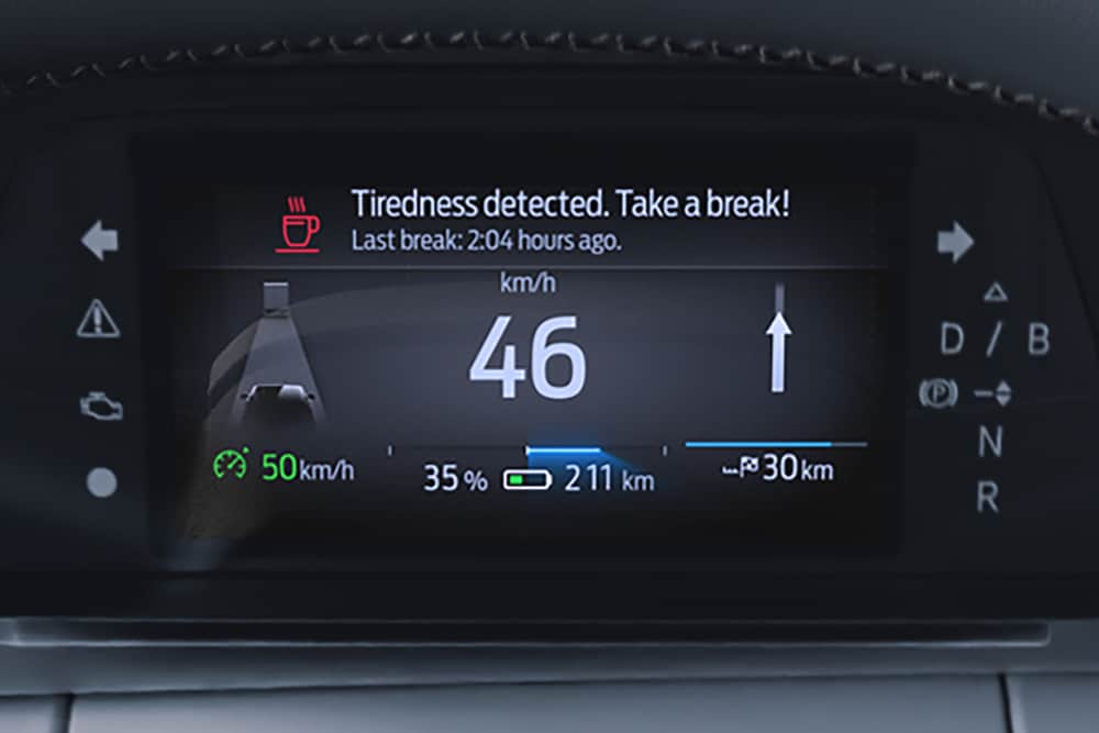 The Ford Capri digital instrument cluster showing the car's speed and a Driver Alert warning message recommending a break.