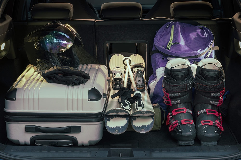 The rear luggage space of the Ford Explorer filled with a white suitcase and ski equipment placed through the luggage hatch.