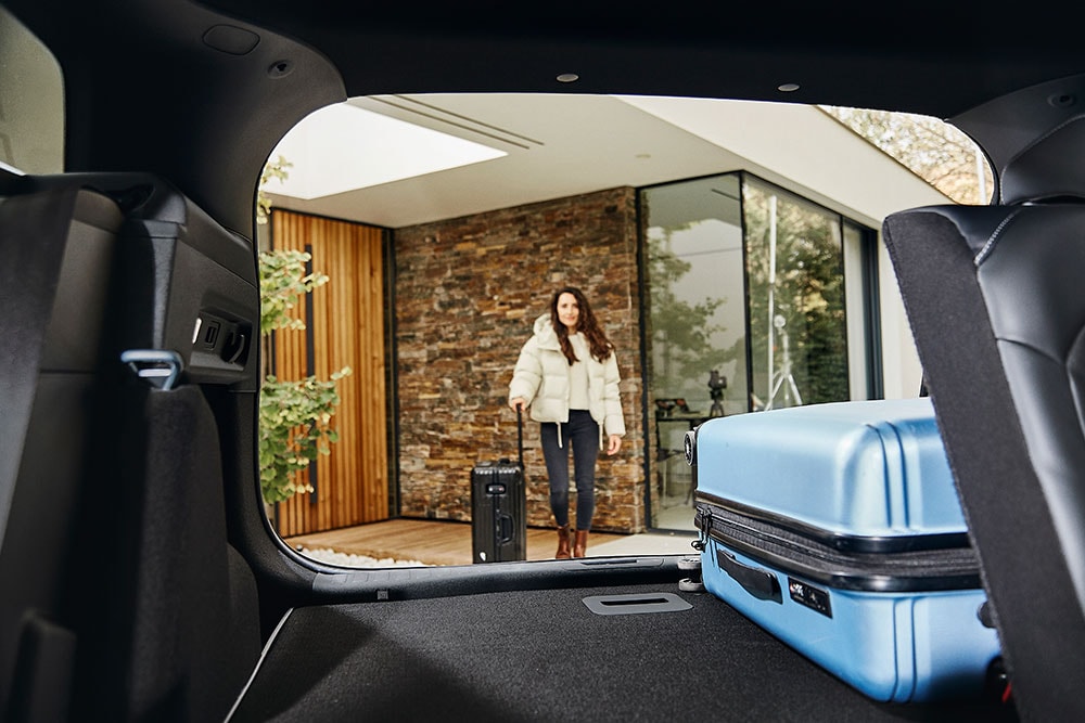 The rear luggage space of the Ford Explorer, taken from the inside of the car, including a blue suitcase.