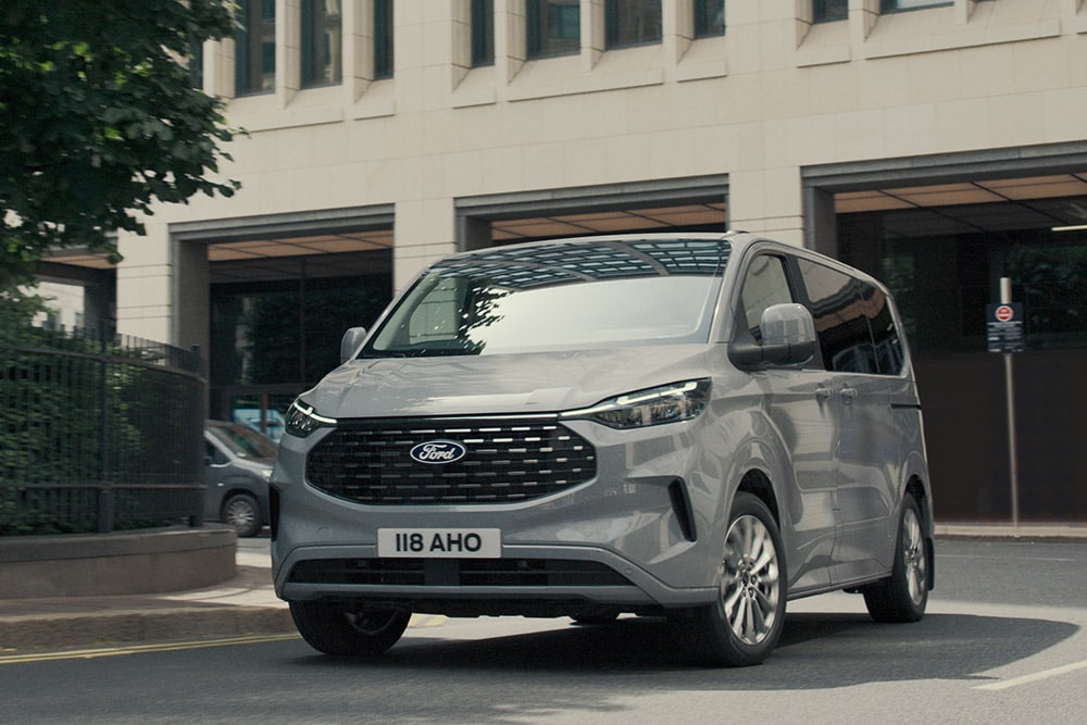 Front 3/4 view of a grey Ford Transit Custom on a city street.