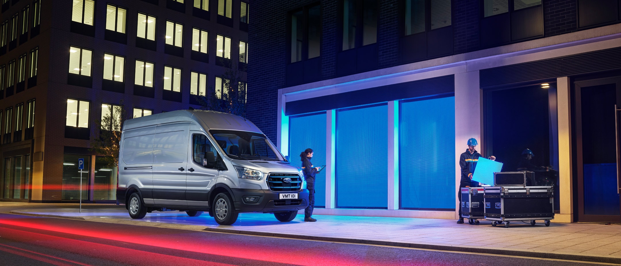 New Ford E-Transit in front of depot in city in night 3/4 front view