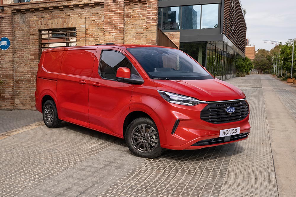Delivery driver loading packages into a red Ford E-Transit Custom.