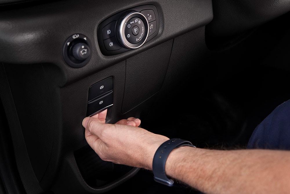 Close-up of a hand pressing a button on the dashboard of a Ford E-Transit electric van.