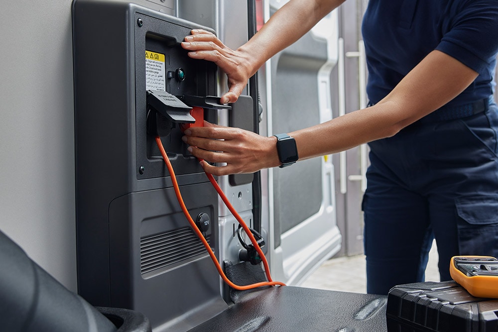  Close-up of a person plugging in a charging cable inside a Ford E-Transit electric van.
