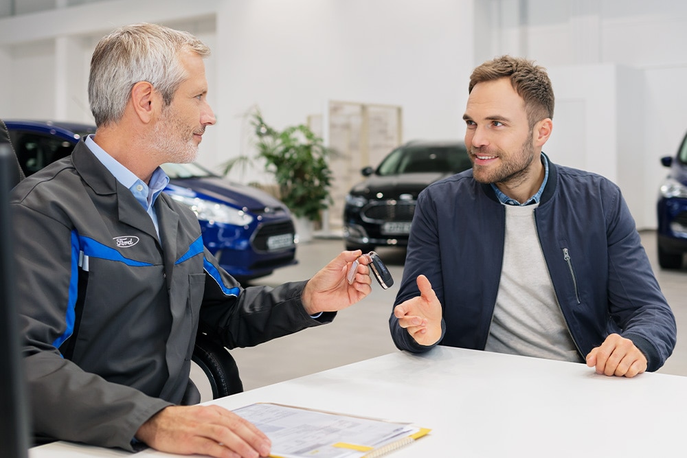 Ford consultant hands a customer keys while discussing the range of Ford financing options.