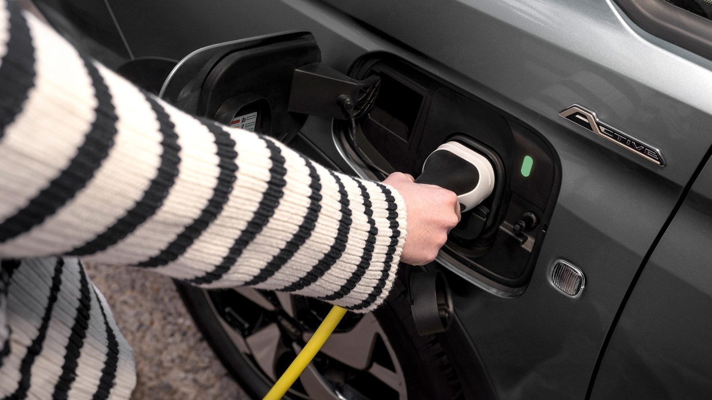 A charging cable plugged into the port of Ford Transit Connect in Graphite Grey
