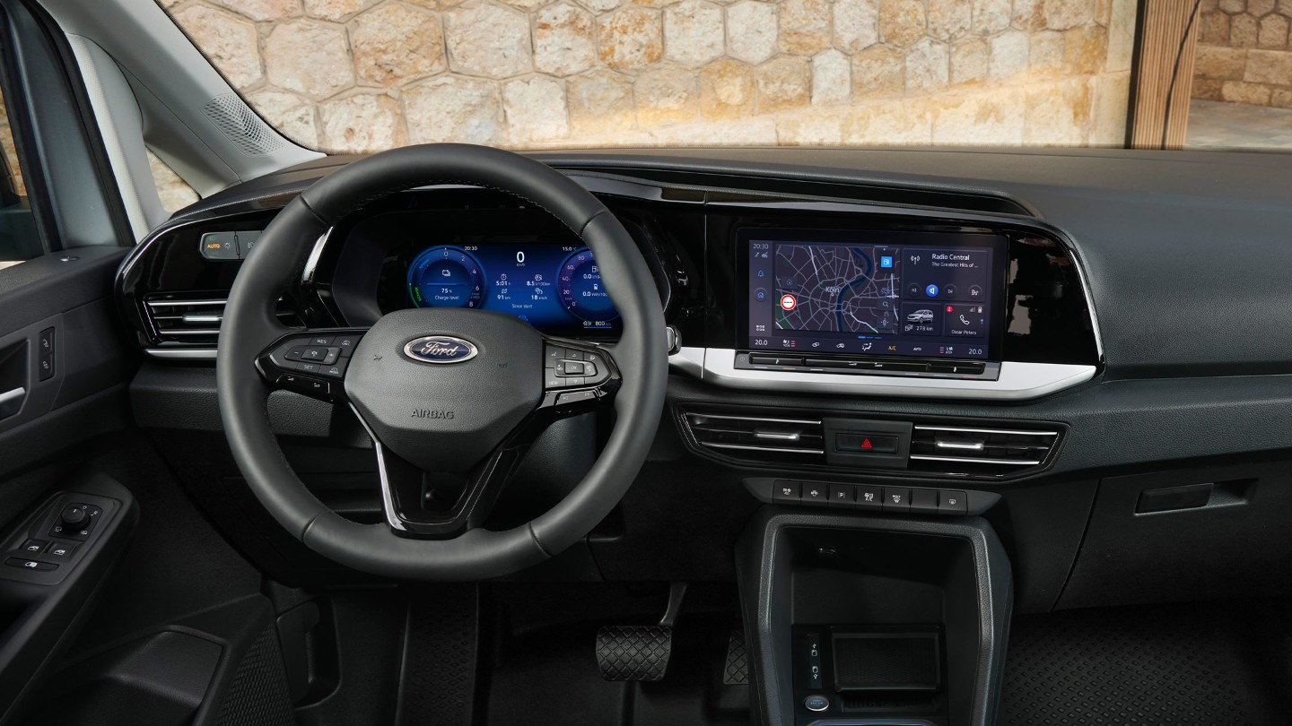 Front interior of All-New Ford Transit Connect showing steering wheel, digital instrument cluster and 10” touchscreen. 