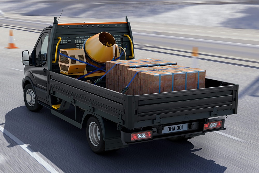 Ford Transit Chassis Cab driving with cargo and a cement mixer in the loadbed.