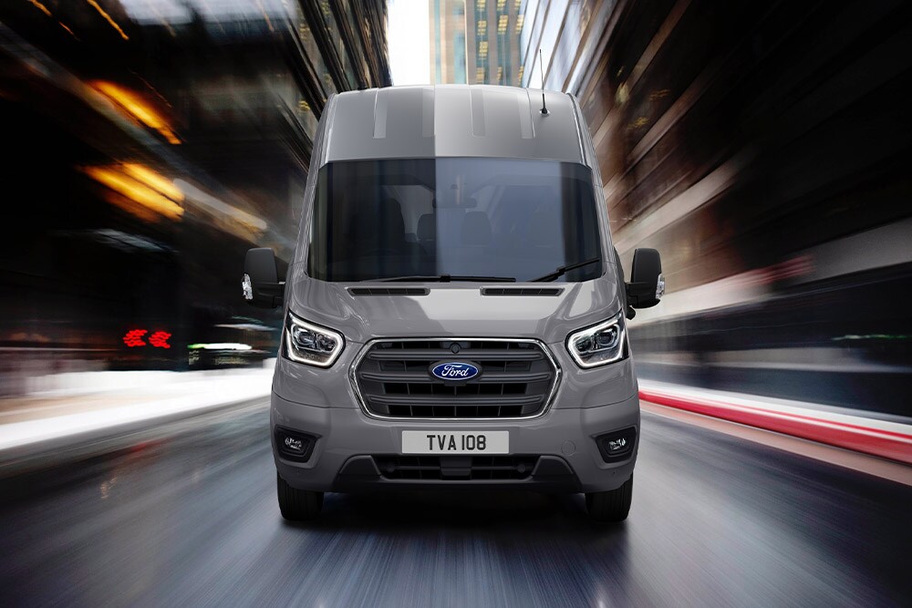 Front grille and windscreen view of a grey Ford Transit driving on a street.