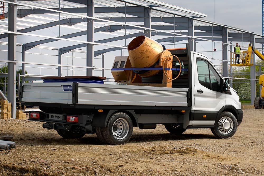 Ford Transit Chassis Cab carrying a cement mixer in the loadbed parked on a building site.