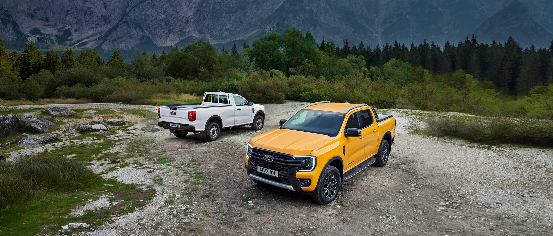 Orange Ford Ranger 3/4 front view on gravel in front of Blue Ford Ranger 3/4 rear view