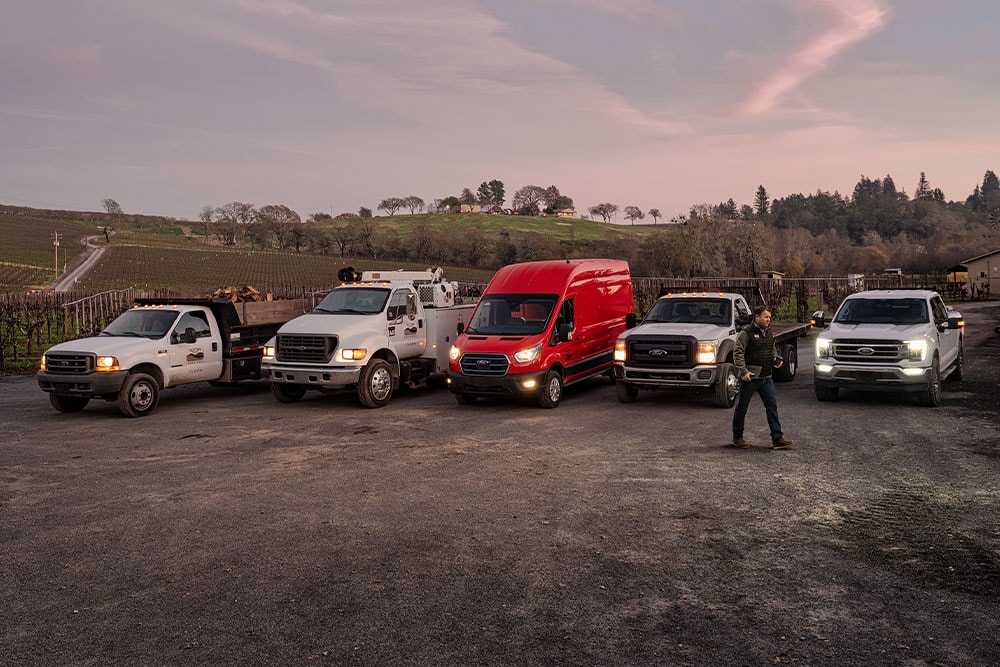 VIDEO – A row of different Ford Pro vehicle models parked in a lot at dusk.