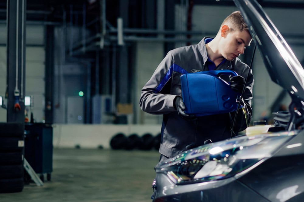 Side view of a Ford-approved technician repairing a vehicle in a garage.