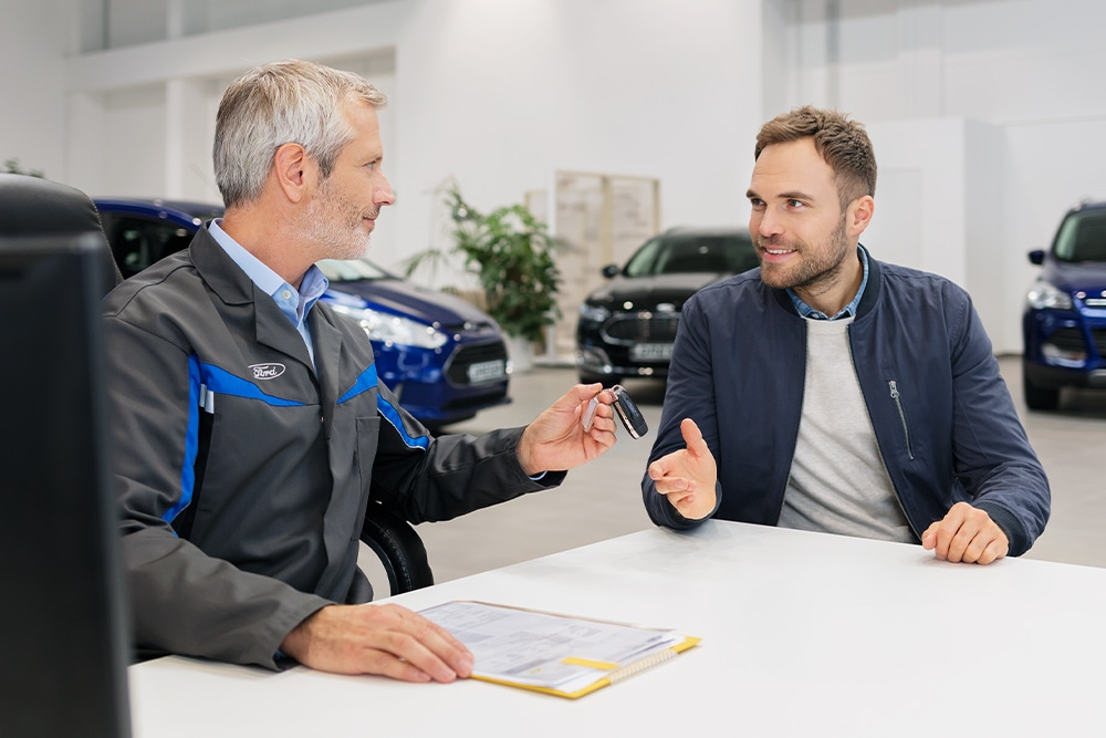 Two men sitting across from each other at a Ford dealership.