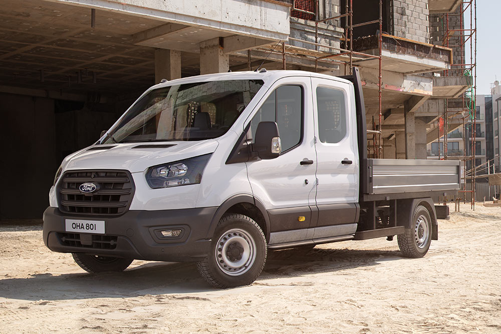 White Ford Pro Chassis Cab parked on a building site next to two construction workers.