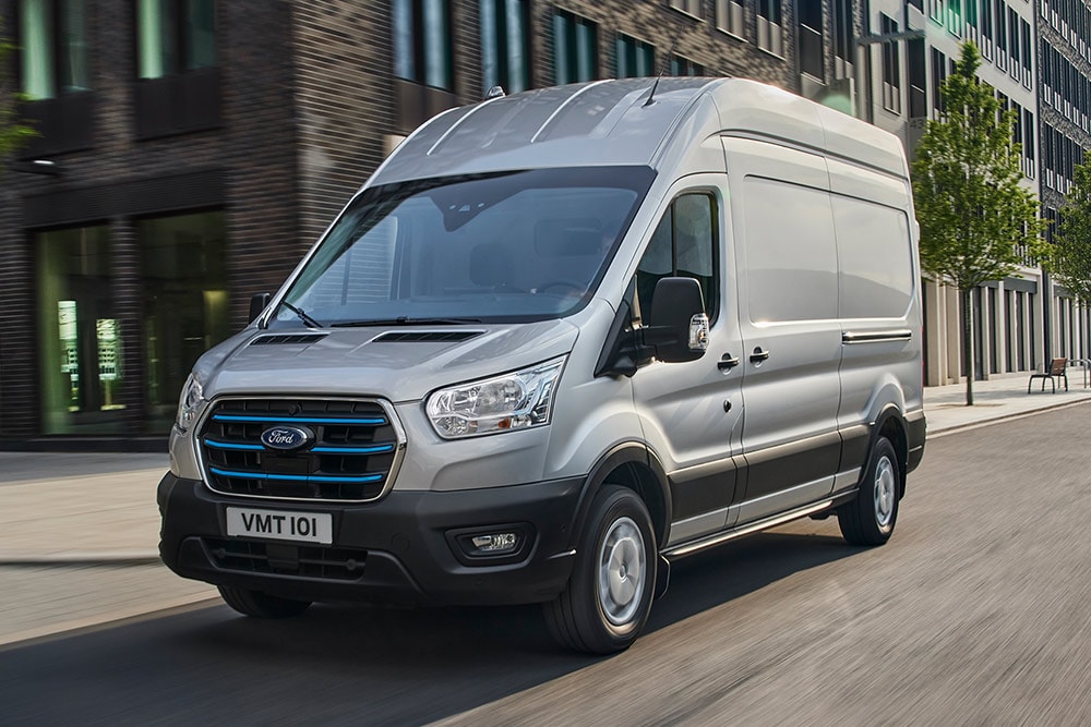 A silver Ford Transit driving through an urban landscape.
