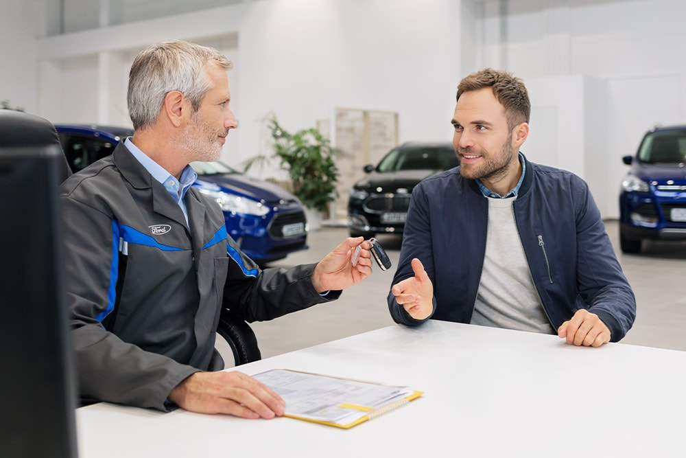 Two men sitting across from each other at a Ford dealership.