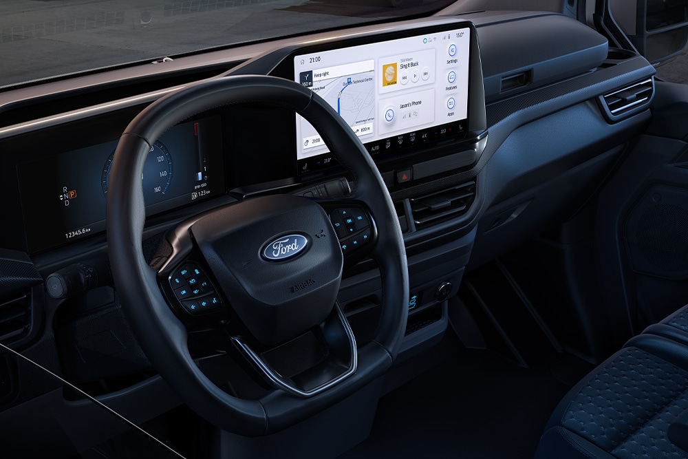 Interior view of a Ford vehicle with a large digital dashboard, showing a worksite through the windshield.