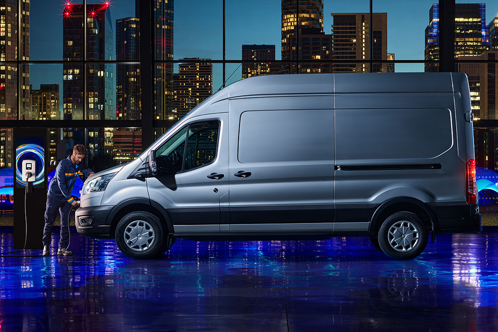 Man charging a white Ford Transit, a vibrant city skyline in the background.