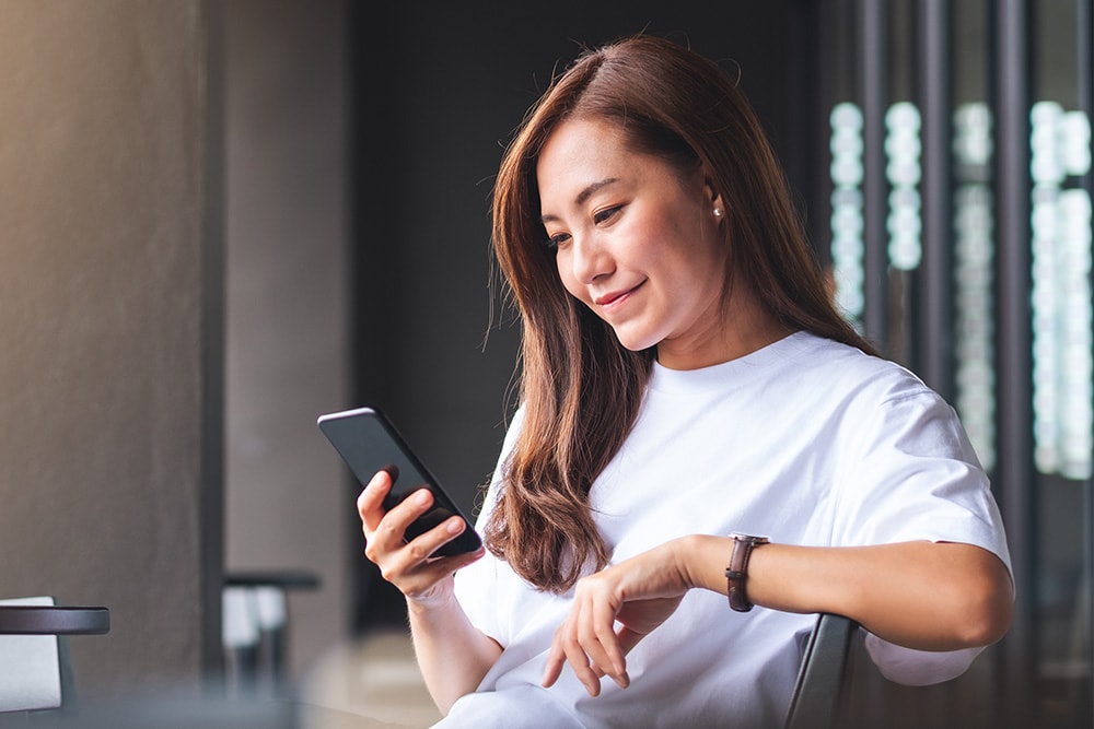 Woman checking real time alerts from the FordPass app on her mobile device.