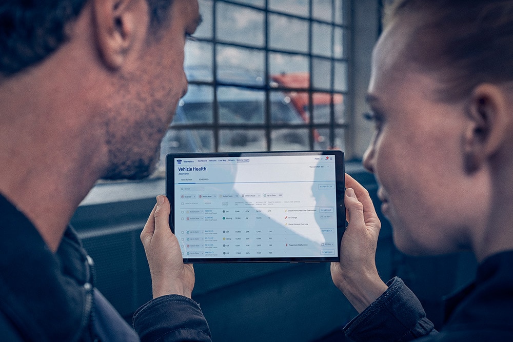 Fleet managers looking at vehicle telematics on a tablet.