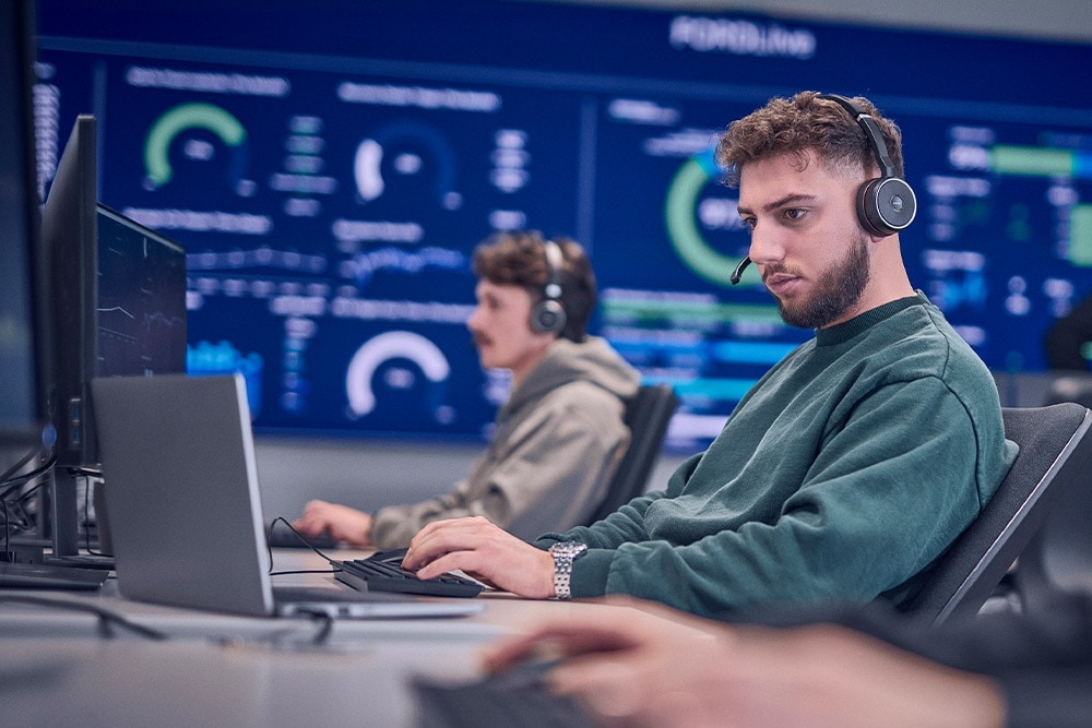 A Ford worker wearing a headset and working on his laptop.