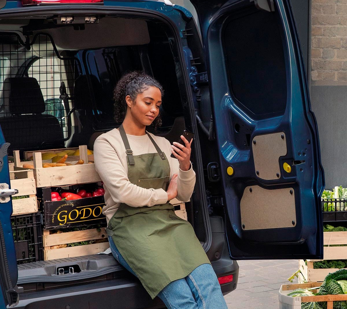 Woman with a phone leaning on to Ford Transit Courier